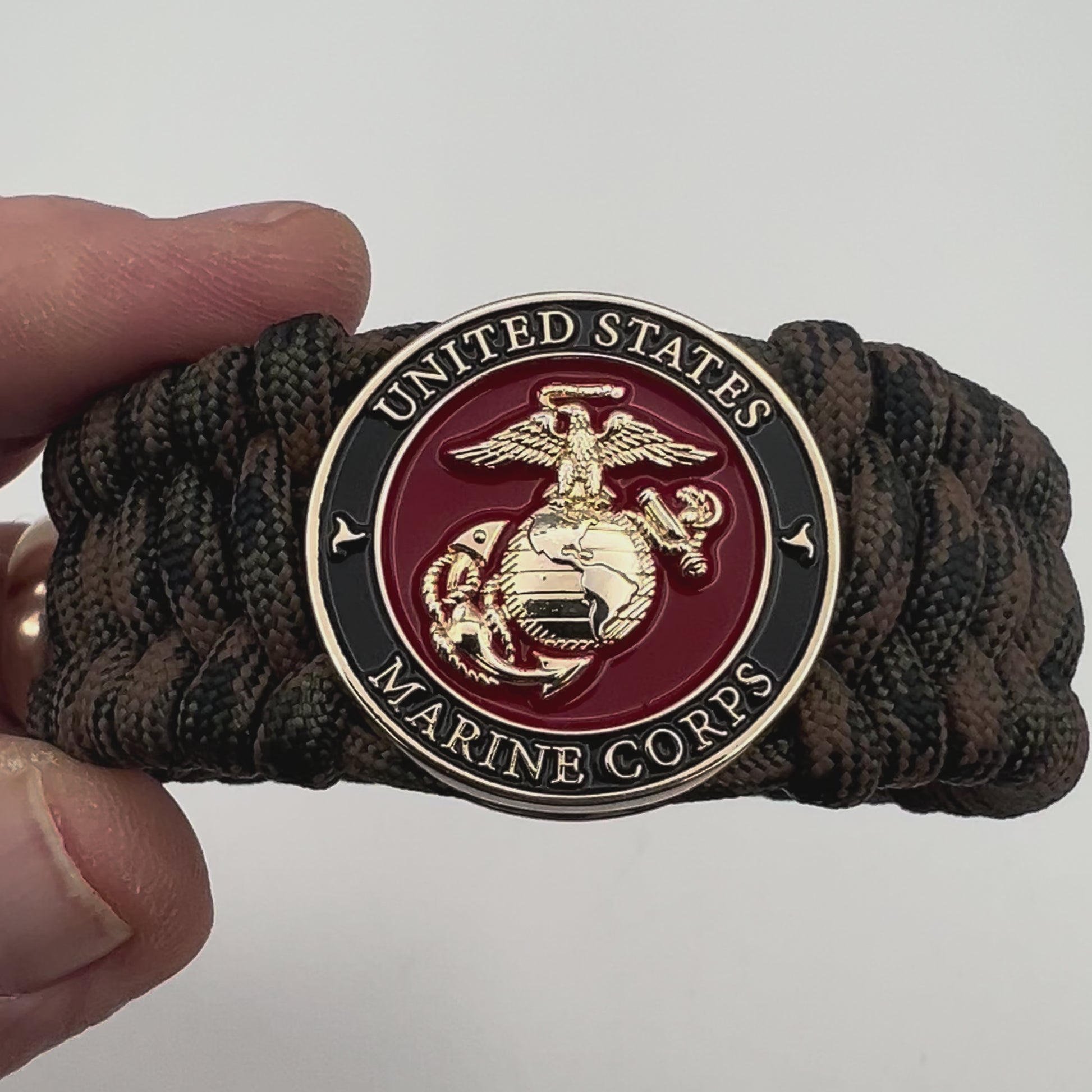 Thick, wide, semi-rigid and comfortable braided United States Marine Corps bracelet featuring a 24K gold plated USMC Eagle Globe and Anchor medallion, a gold Cobra style tactical buckle and woven with Woodland Camo 550 paracord.