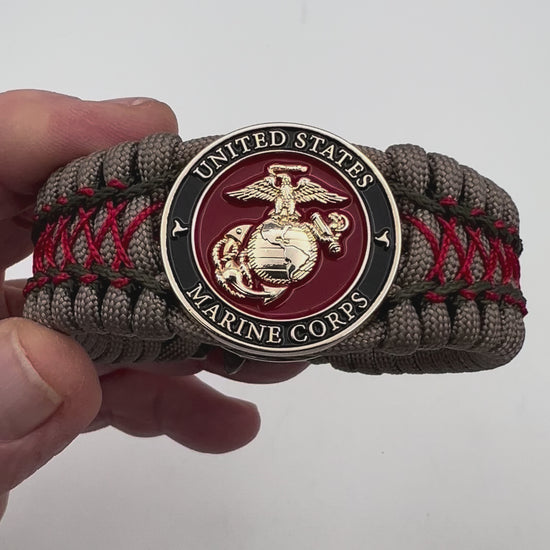 Thick, wide, rigid and comfortable braided United States Marine Corps bracelet featuring a 24K gold plated USMC Eagle Globe and Anchor medallion, a gold Cobra style tactical buckle and woven with tan 550 paracord, olive drab micro and Imperial red nano cord.
