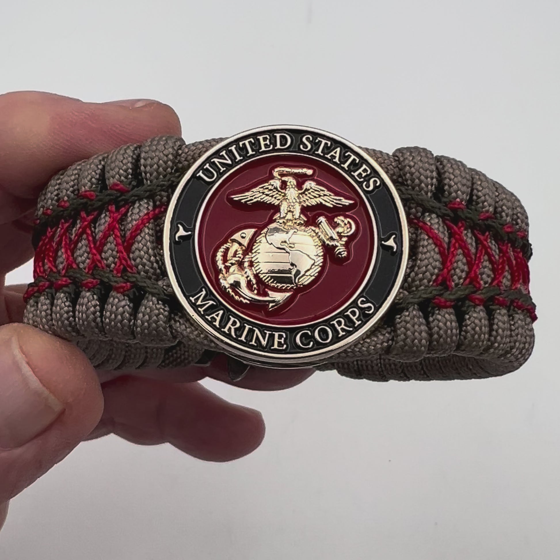 Thick, wide, rigid and comfortable braided United States Marine Corps bracelet featuring a 24K gold plated USMC Eagle Globe and Anchor medallion, a gold Cobra style tactical buckle and woven with tan 550 paracord, olive drab micro and Imperial red nano cord.