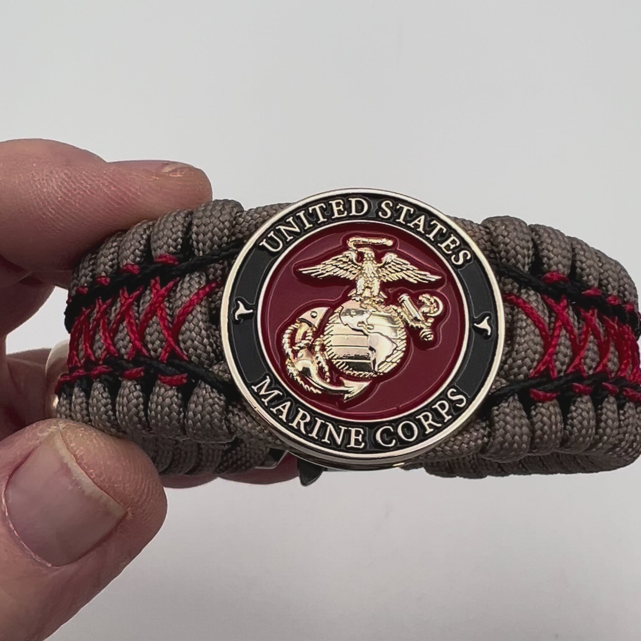 Thick, wide, rigid and comfortable handwoven United States Marine Corps bracelet featuring a 24K gold plated USMC Eagle Globe and Anchor medallion, a gold Cobra style tactical buckle and woven with tna 550 paracord, black micro cord and red nano cord.
