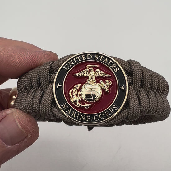 Thick, semi-rigid and comfortable braided United States Marine Corps bracelet featuring a 24K gold plated USMC Eagle Globe and Anchor medallion, a gold Cobra style tactical buckle and woven with tan 550 paracord.