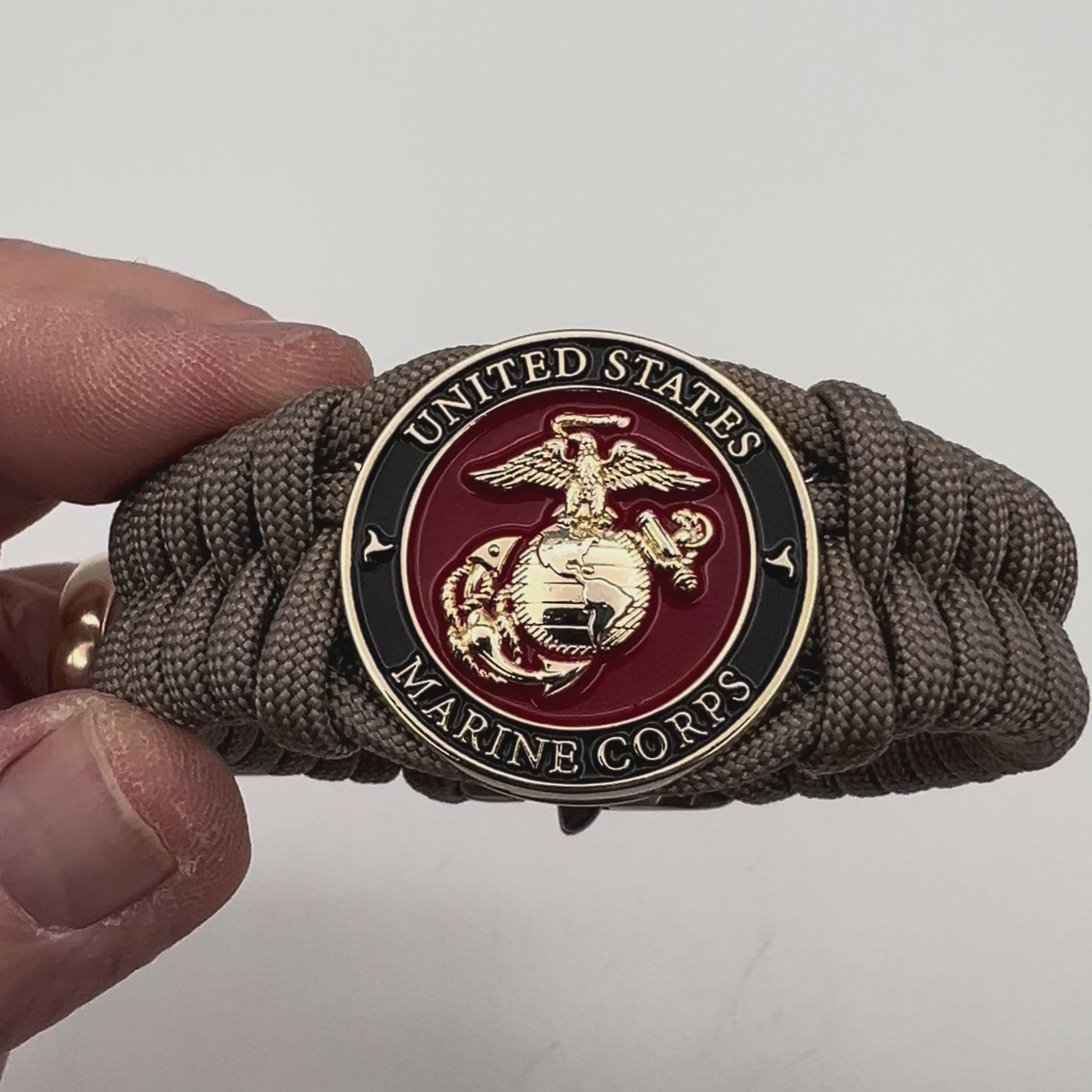 Thick, semi-rigid and comfortable braided United States Marine Corps bracelet featuring a 24K gold plated USMC Eagle Globe and Anchor medallion, a gold Cobra style tactical buckle and woven with tan 550 paracord.