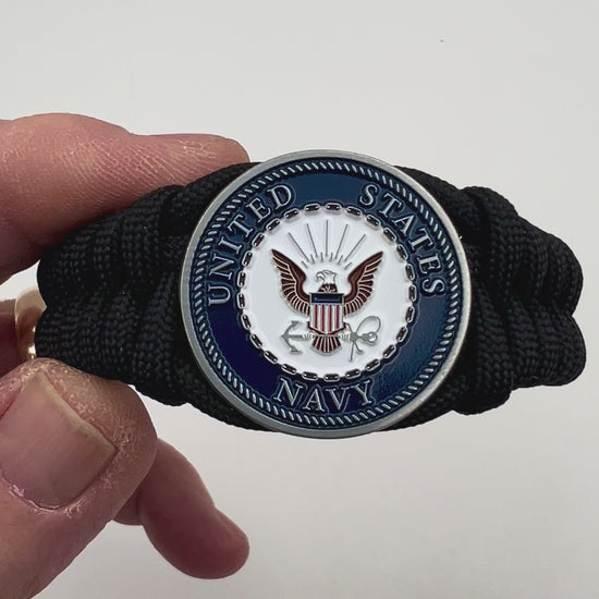 Thick, narrow, and semi-rigid braided United States Navy bracelet featuring an antique silver plated Navy medallion, a black Cobra style tactical buckle and woven with black 550 paracord.