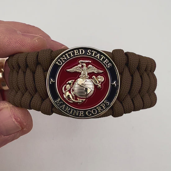 Thick and comfortable braided United States Marine Corps bracelet featuring a 24K gold and silver plated USMC officer Eagle Globe and Anchor medallion, a Cobra style tactical buckle and woven with Coyote Brown 550 paracord.
