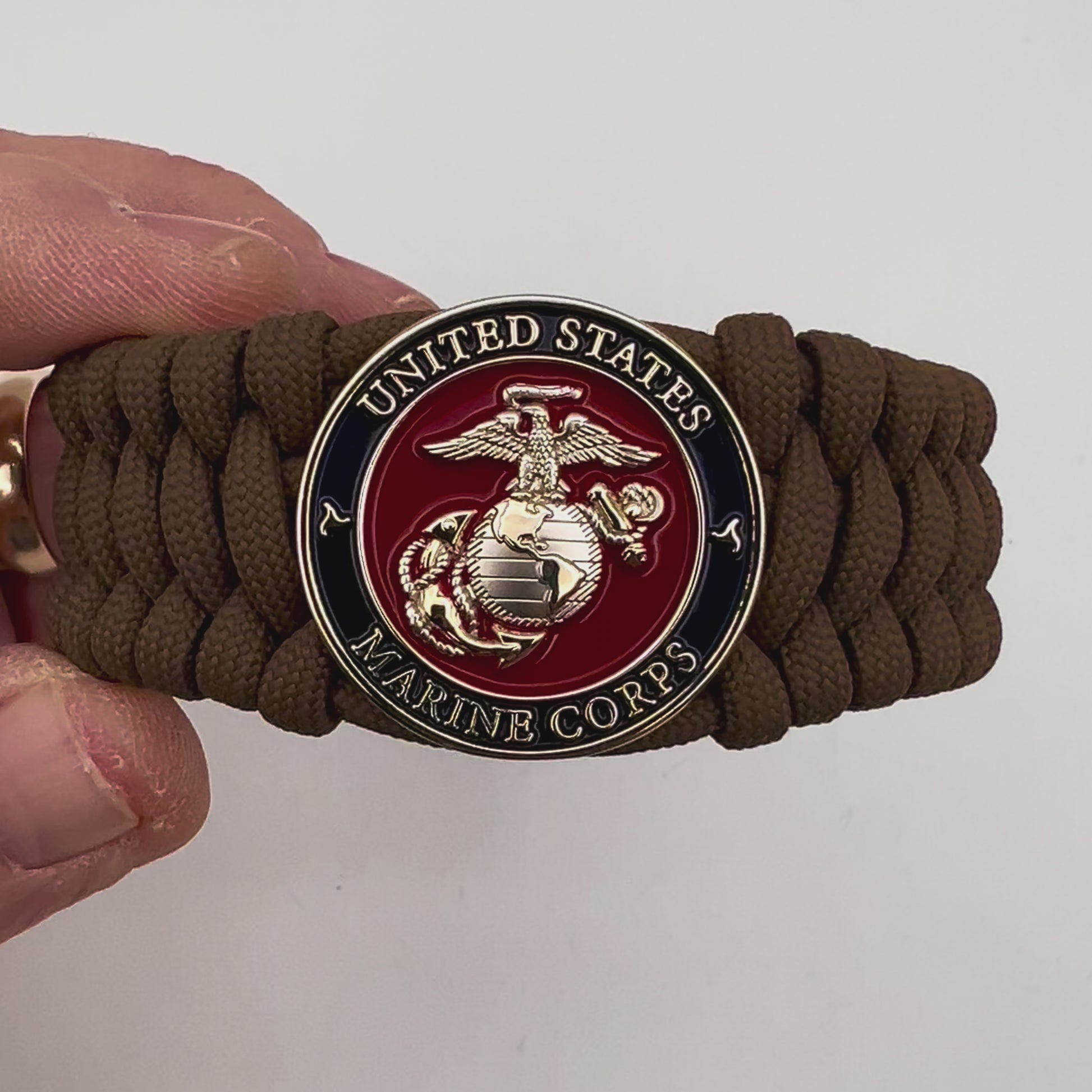 Thick and comfortable braided United States Marine Corps bracelet featuring a 24K gold and silver plated USMC officer Eagle Globe and Anchor medallion, a Cobra style tactical buckle and woven with Coyote Brown 550 paracord.