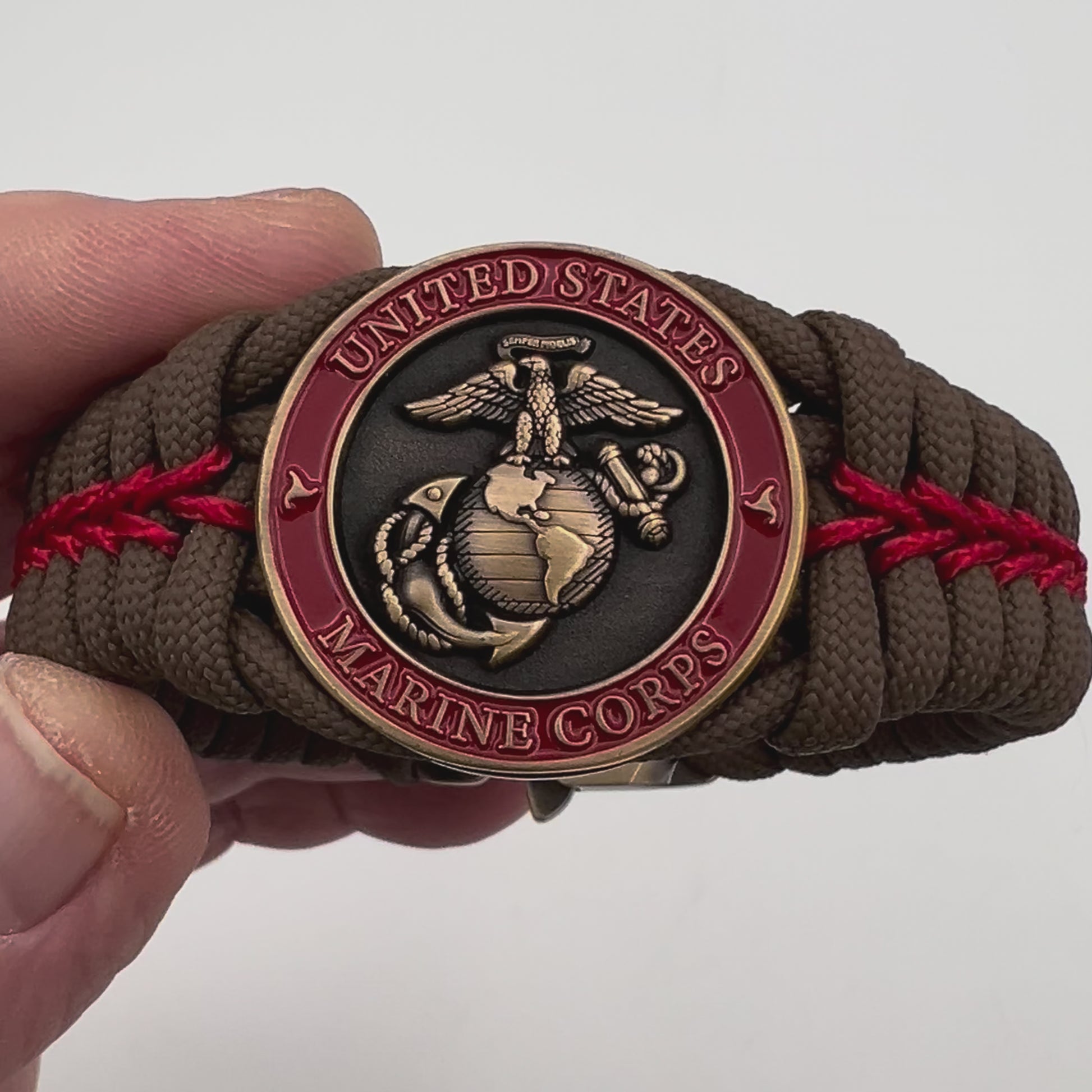 Thick, medium width, semi-rigid and comfortable braided United States Marine Corps bracelet featuring a 24K antique gold plated USMC Eagle Globe and Anchor medallion, a gold Cobra style tactical buckle and woven with Coyote Brown 550 paracord and Imperial Red micro cord.