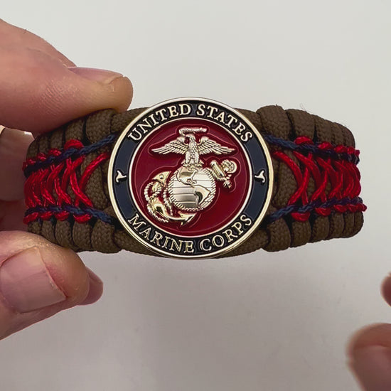 Thick and comfortable braided United States Marine Corps bracelet featuring a 24K gold and silver plated USMC officer Eagle Globe and Anchor medallion, a Cobra style tactical buckle and woven with Coyote Brown 550 paracord and Imperial Red and Navy Blue micro cord.