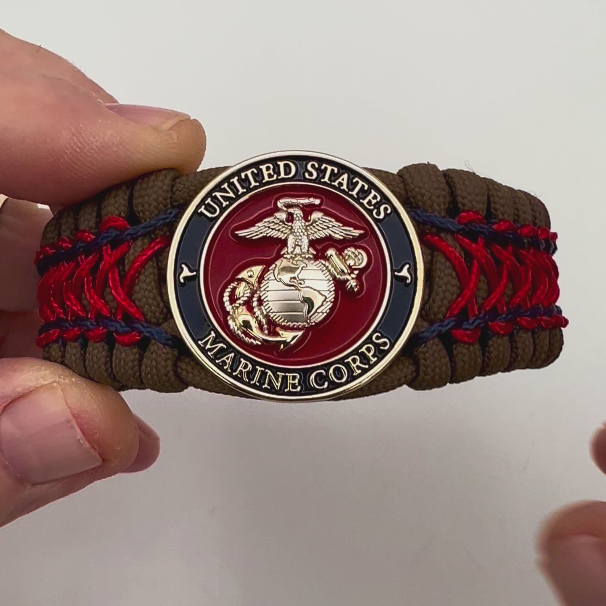 Thick and comfortable braided United States Marine Corps bracelet featuring a 24K gold and silver plated USMC officer Eagle Globe and Anchor medallion, a Cobra style tactical buckle and woven with Coyote Brown 550 paracord and Imperial Red and Navy Blue micro cord.