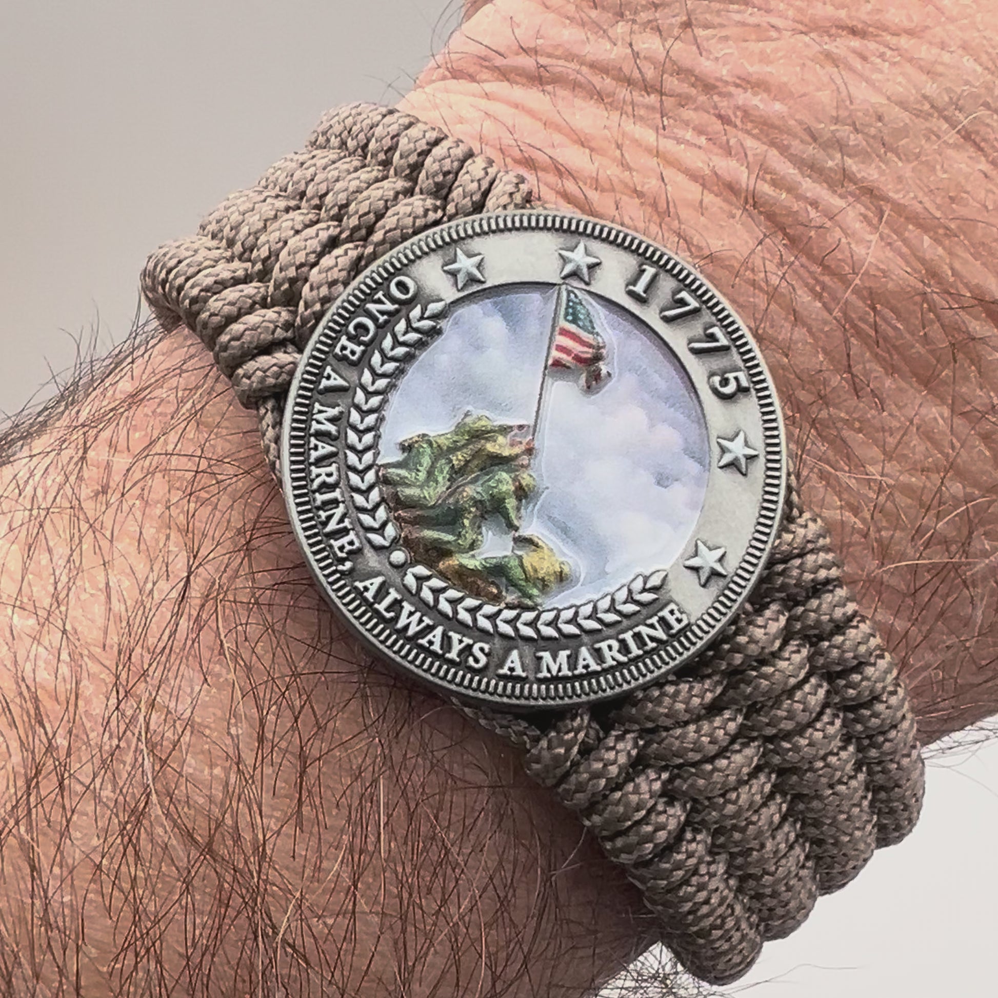 Thin, wide, flexible and comfortable braided United States Marine Corps Iwo Jima bracelet featuring an antique silver plated UV painted Iwo Jima flag raising medallion, a silver Cobra style tactical buckle and woven with tan Type-1 paracord.