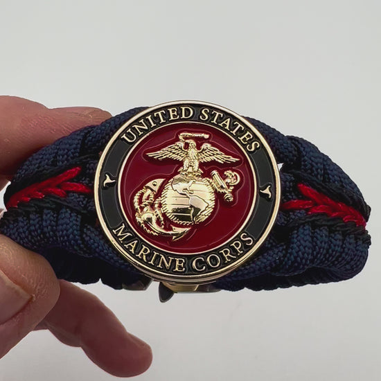 Thick, rigid and comfortable braided United States Marine Corps bracelet featuring a 24K gold plated USMC Eagle Globe and Anchor medallion, a gold Cobra style tactical buckle and woven with Navy Blue 550 paracord and Imperial Red and Black micro cord.