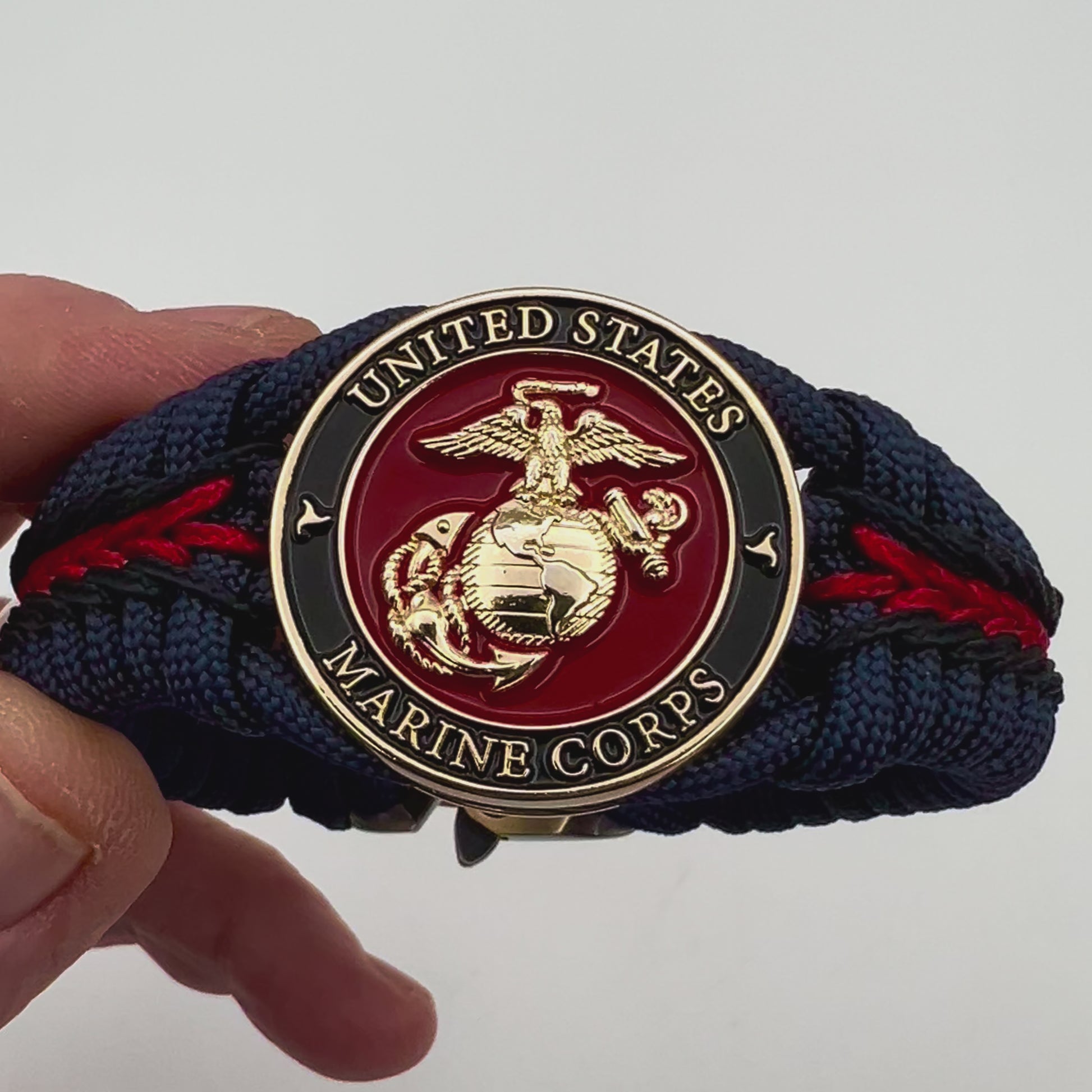 Thick, rigid and comfortable braided United States Marine Corps bracelet featuring a 24K gold plated USMC Eagle Globe and Anchor medallion, a gold Cobra style tactical buckle and woven with Navy Blue 550 paracord and Imperial Red and Black micro cord.