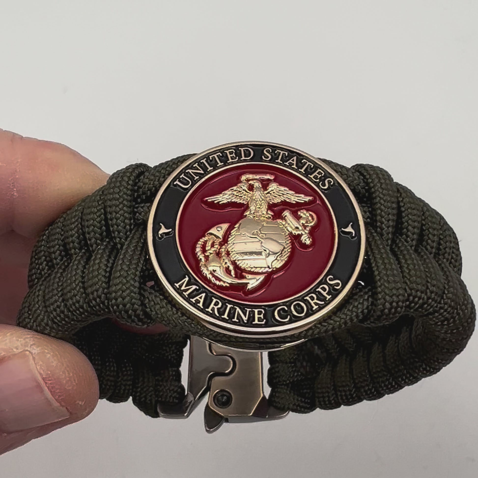 Thick, semi-rigid and comfortable braided United States Marine Corps bracelet featuring a 24K gold plated USMC officer Eagle Globe and Anchor medallion, a gold Cobra style tactical buckle and woven with olive drab 550 paracord.