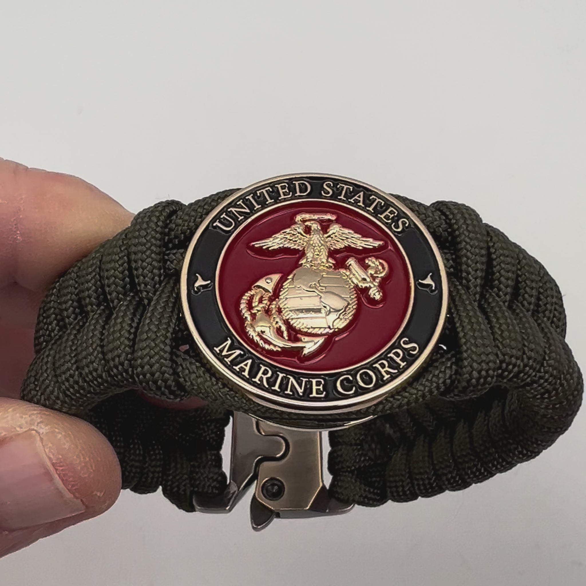 Thick, semi-rigid and comfortable braided United States Marine Corps bracelet featuring a 24K gold plated USMC officer Eagle Globe and Anchor medallion, a gold Cobra style tactical buckle and woven with olive drab 550 paracord.