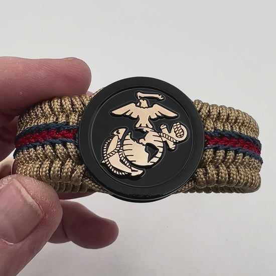 Thin, medium width, flexible and comfortable braided United States Marine Corps bracelet featuring a gold USMC Eagle Globe and Anchor medallion, a gold Cobra style tactical buckle and woven with gold Type-1 paracord and stitched with red and blue nano cord.