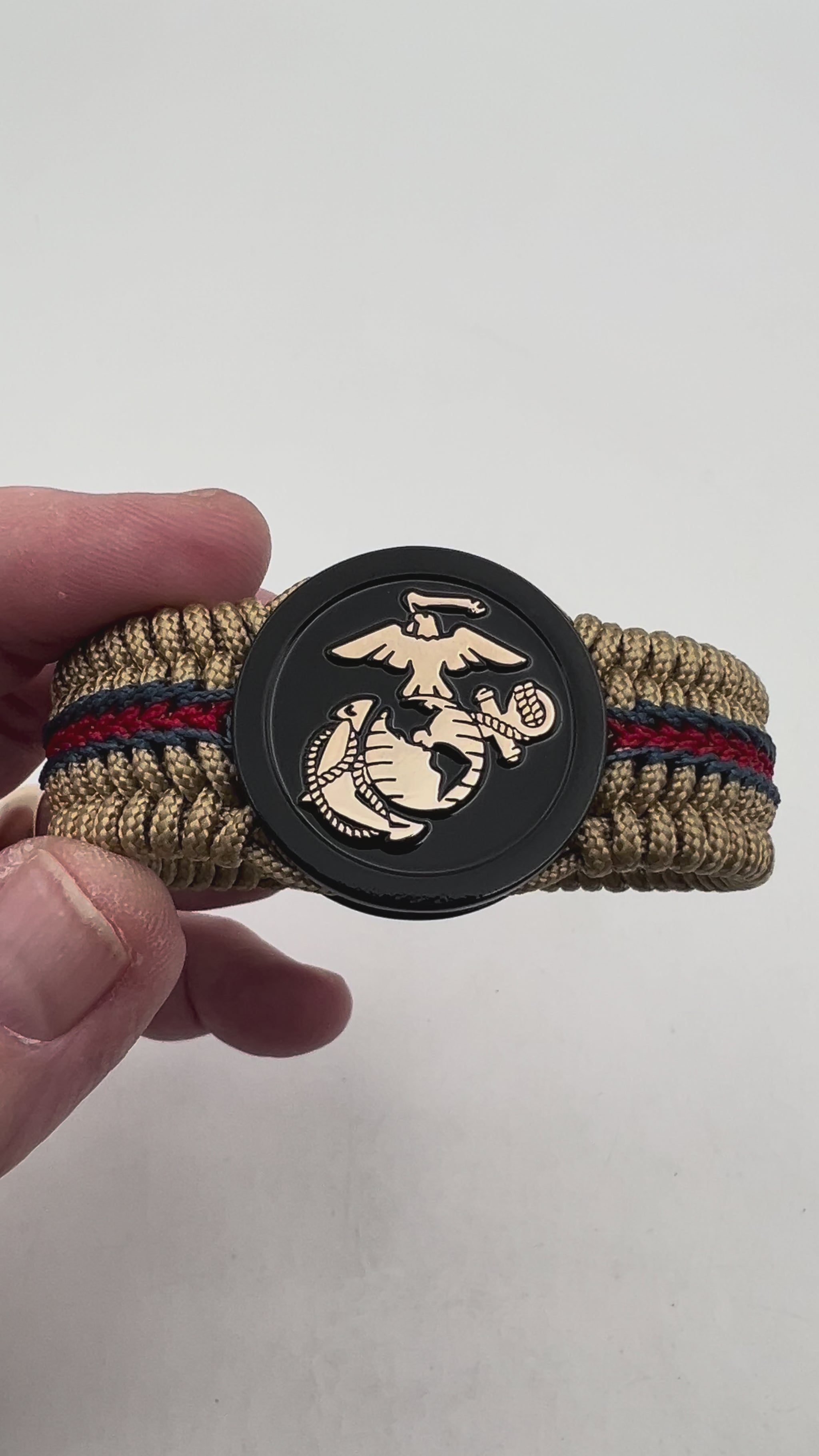 Thin, medium width, flexible and comfortable braided United States Marine Corps bracelet featuring a gold USMC Eagle Globe and Anchor medallion, a gold Cobra style tactical buckle and woven with gold Type-1 paracord and stitched with red and blue nano cord.