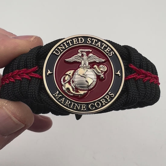 Thick, semi-rigid and comfortable braided United States Marine Corps bracelet featuring a 24K gold and silver plated USMC officer Eagle Globe and Anchor medallion, a black Cobra style tactical buckle and woven with black 550 and Imperial red micro paracord.