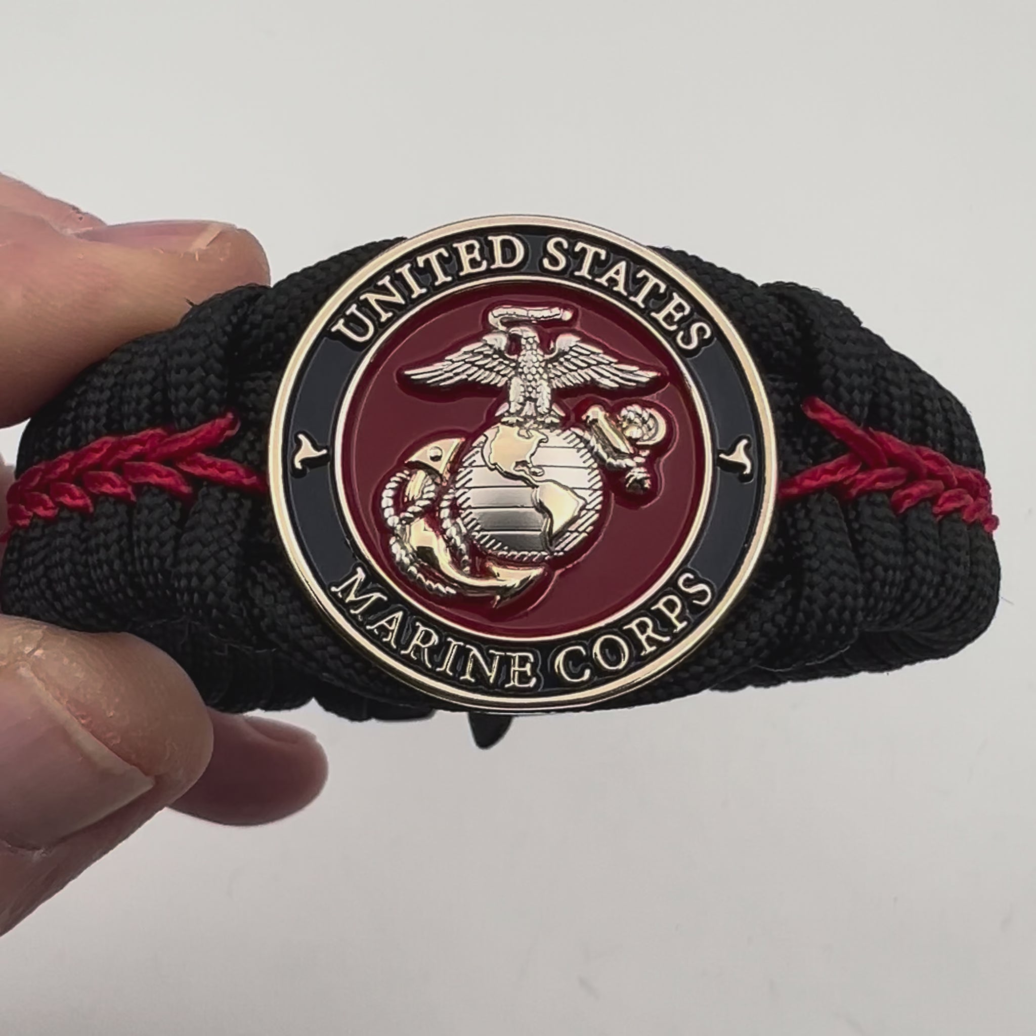Thick, semi-rigid and comfortable braided United States Marine Corps bracelet featuring a 24K gold and silver plated USMC officer Eagle Globe and Anchor medallion, a black Cobra style tactical buckle and woven with black 550 and Imperial red micro paracord.