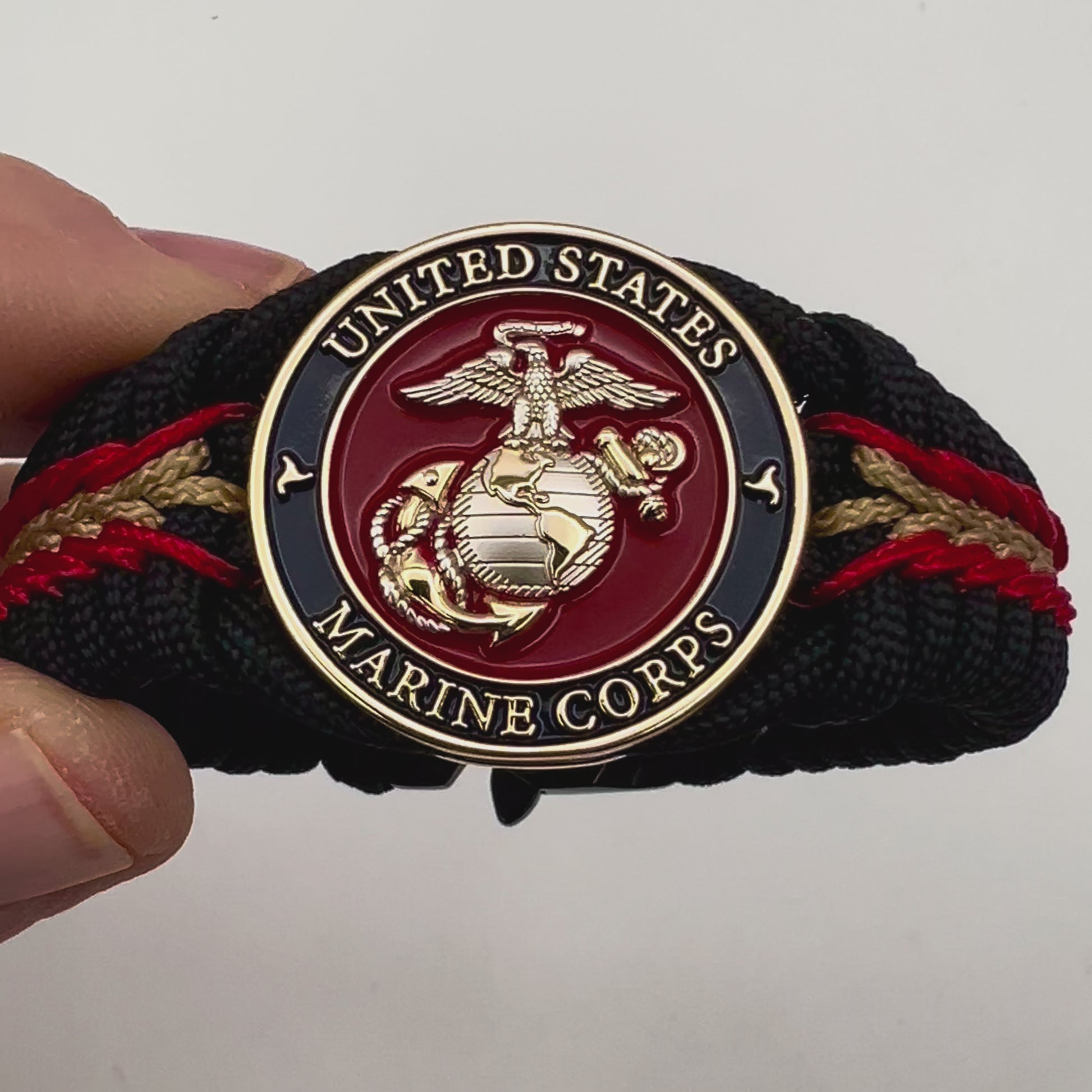 Thick, semi-rigid and comfortable braided United States Marine Corps bracelet featuring a 24K gold and silver plated USMC officer Eagle Globe and Anchor medallion, a black Cobra style tactical buckle and woven with black 550, Imperial red and gold micro paracord.