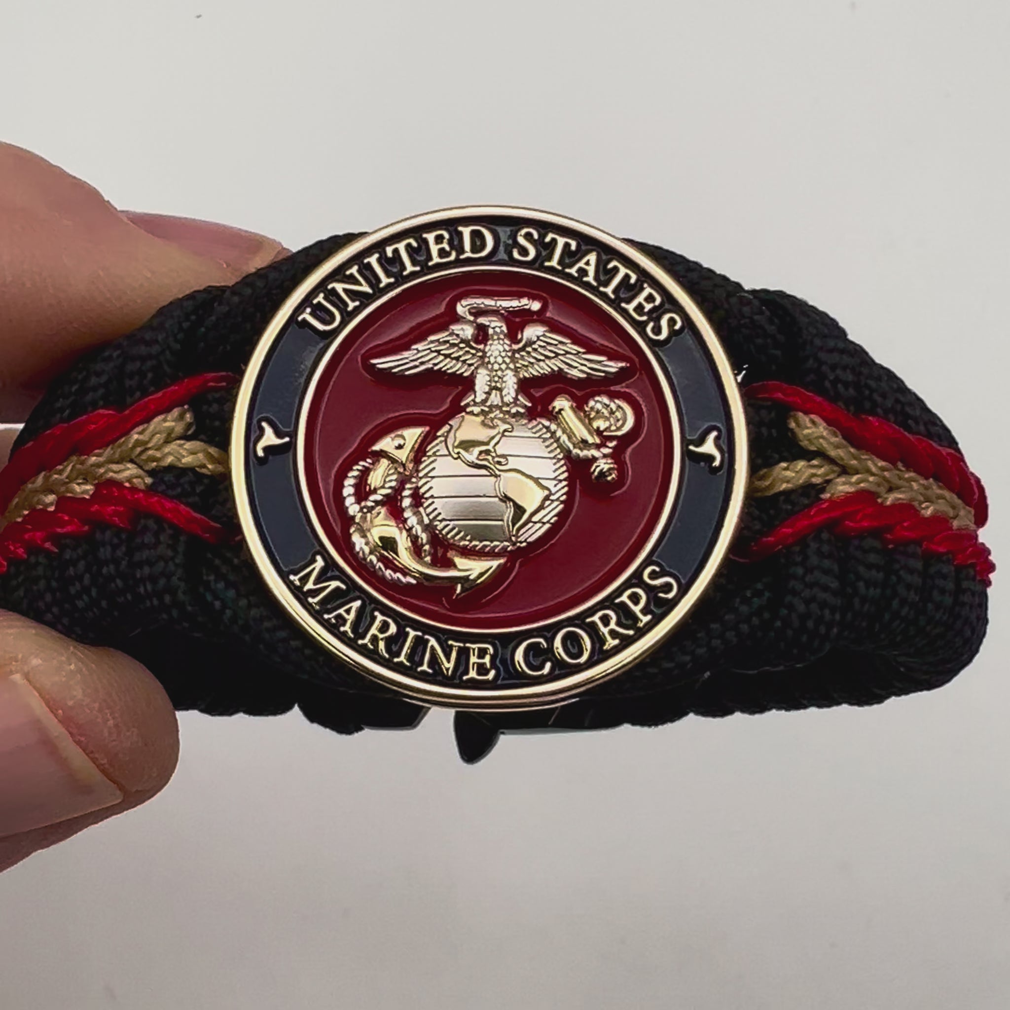 Thick, semi-rigid and comfortable braided United States Marine Corps bracelet featuring a 24K gold and silver plated USMC officer Eagle Globe and Anchor medallion, a black Cobra style tactical buckle and woven with black 550, Imperial red and gold micro paracord.