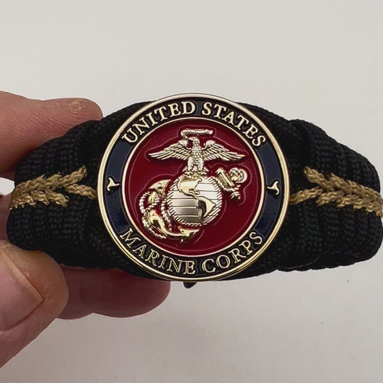 Thick, semi-rigid and comfortable braided United States Marine Corps bracelet featuring a 24K gold and silver plated USMC officer Eagle Globe and Anchor medallion, a black Cobra style tactical buckle and woven with black 550 and gold micro paracord.