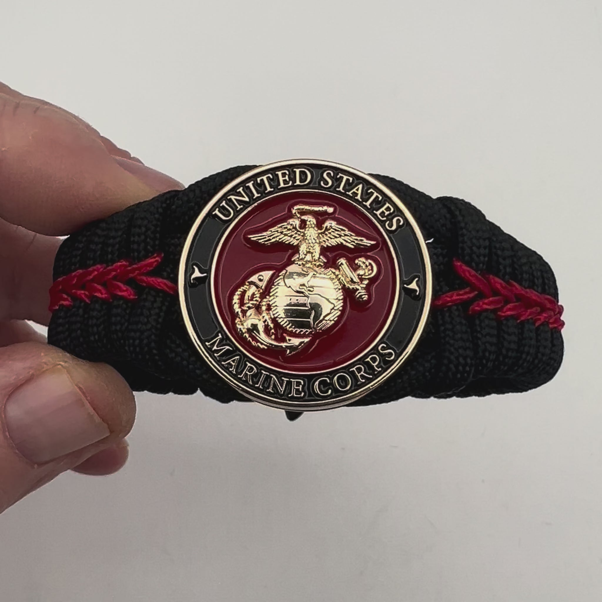 Thick, semi-rigid and comfortable braided United States Marine Corps bracelet featuring a 24K gold plated USMC officer Eagle Globe and Anchor medallion, a black Cobra style tactical buckle and woven with black 550 paracord and Imperial Red micro cord.