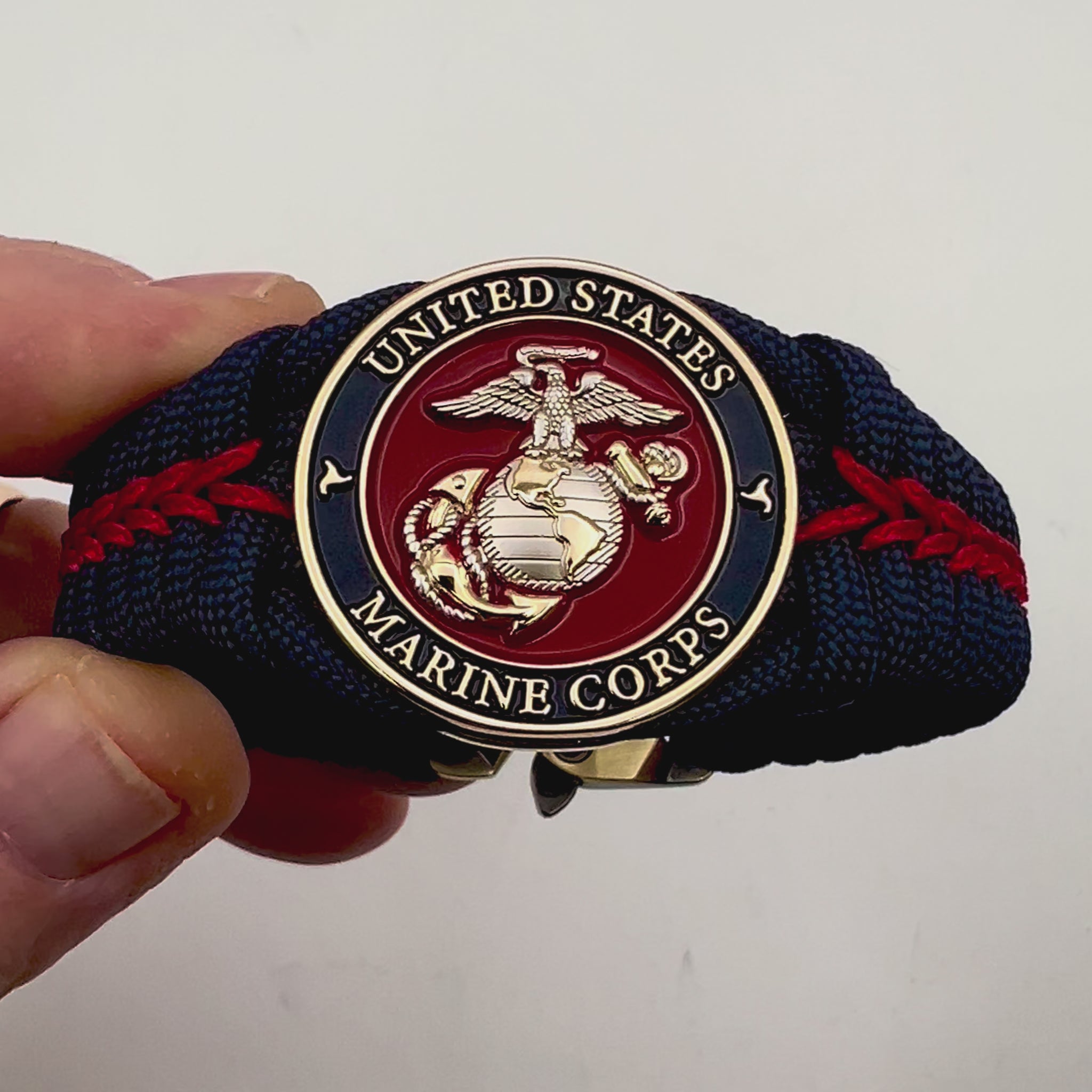 Thick and comfortable braided United States Marine Corps bracelet featuring a 24K gold and silver plated USMC officer Eagle Globe and Anchor medallion, a Cobra style tactical buckle and woven with Navy blue and Imperial red paracord.