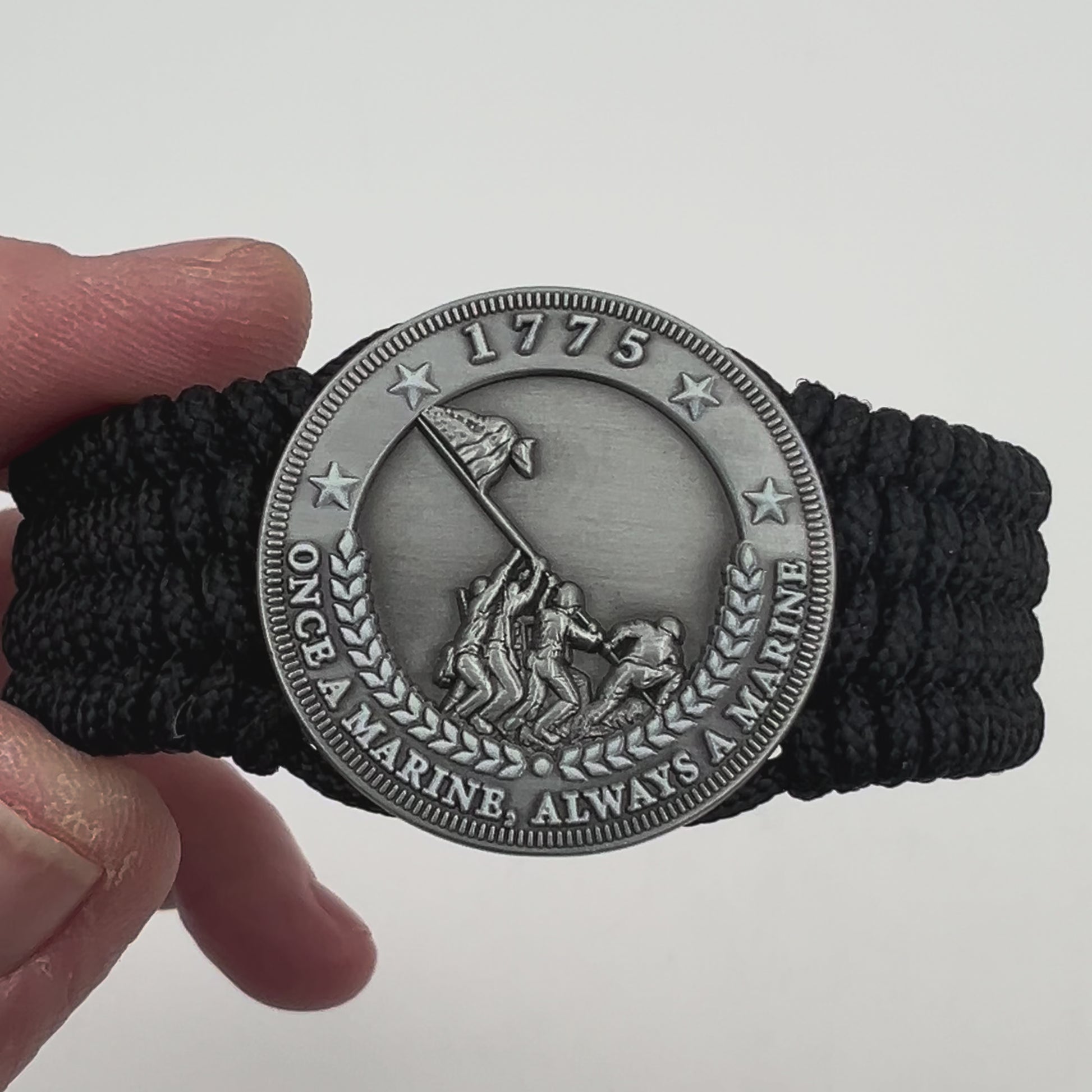 Thin, wide, flexible and comfortable braided United States Marine Corps Iwo Jima bracelet featuring an antique silver plated Iwo Jima flag raising medallion, a black Cobra style tactical buckle and woven with black Type-1 paracord.