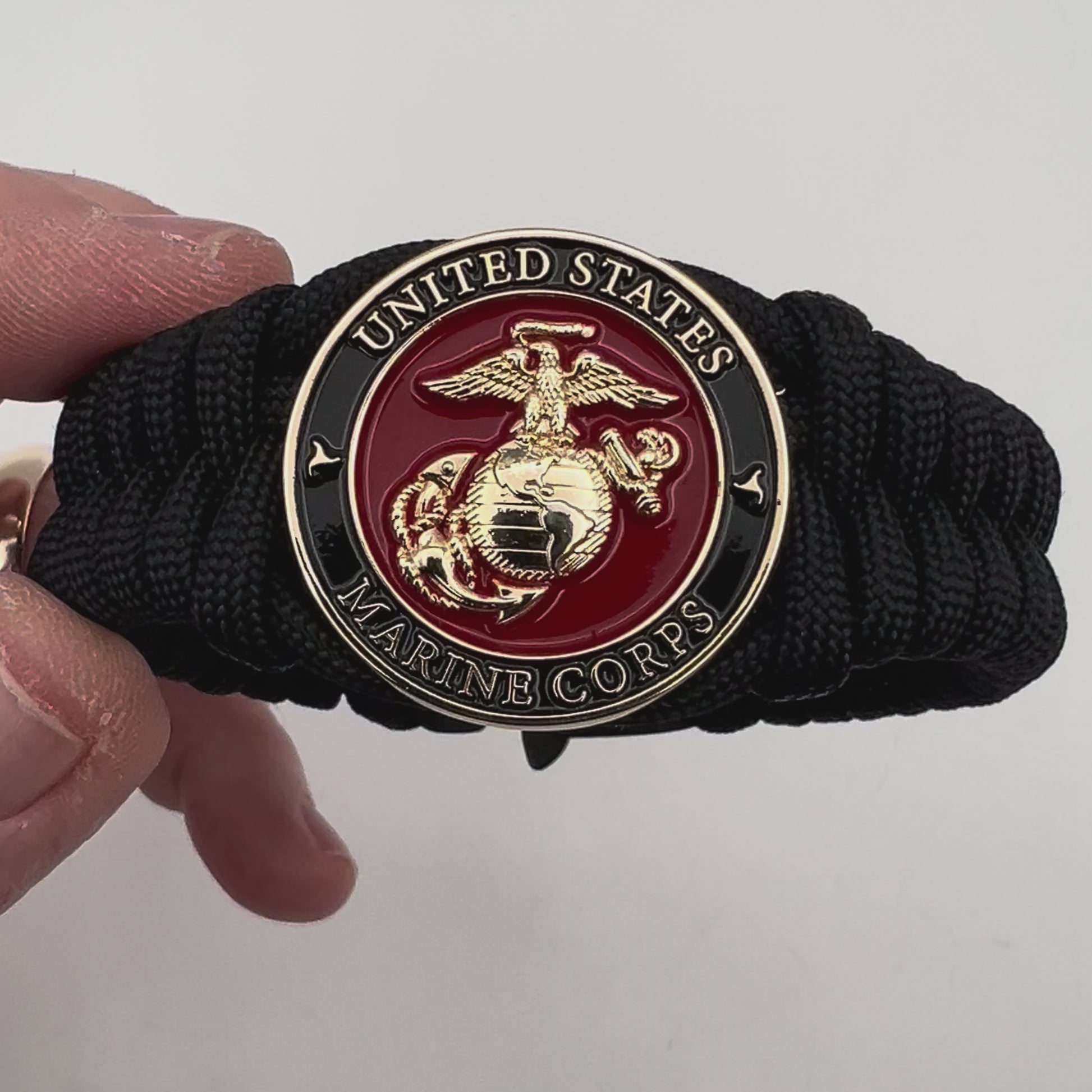 Thick, semi-rigid and comfortable braided United States Marine Corps bracelet featuring a 24K gold plated USMC officer Eagle Globe and Anchor medallion, a black Cobra style tactical buckle and woven with black 550 paracord.