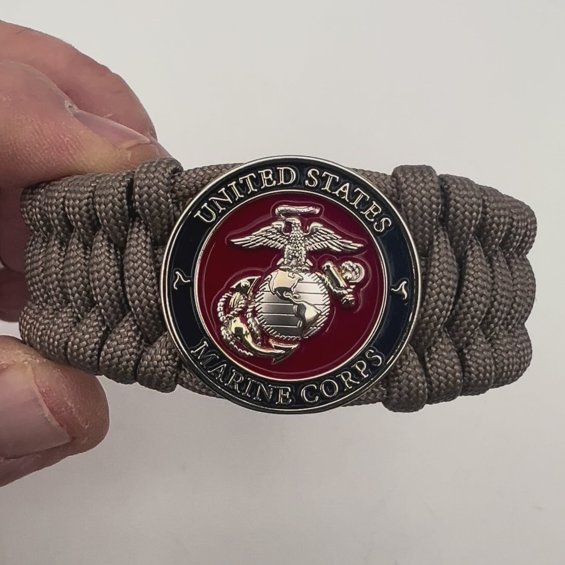 Thick and comfortable braided United States Marine Corps bracelet featuring a 24K gold and silver plated USMC officer Eagle Globe and Anchor medallion, a Cobra style tactical buckle and woven with tan 550 paracord.
