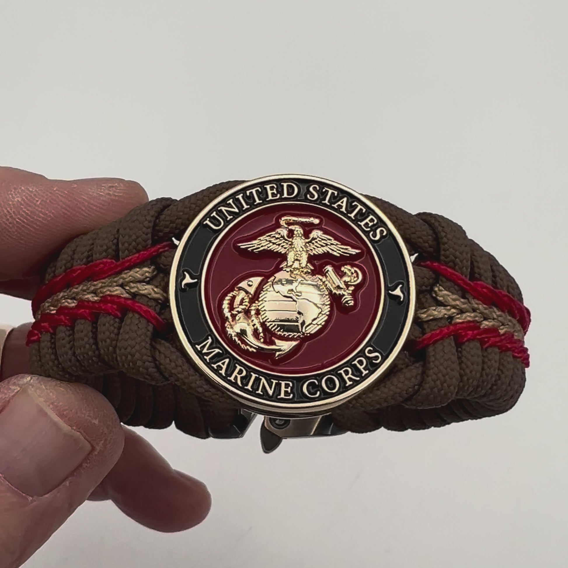 Thick, rigid and comfortable braided United States Marine Corps bracelet featuring a 24K gold plated USMC Eagle Globe and Anchor medallion, a gold Cobra style tactical buckle and woven with Coyote Brown 550 paracord and Imperial Red and gold micro cord.