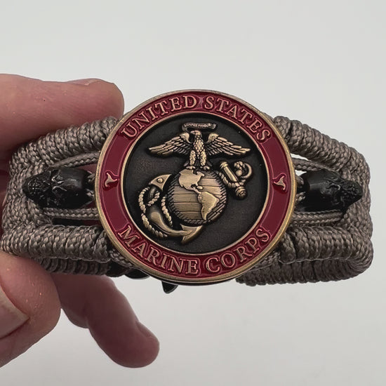 Thin, medium width, flexible and comfortable braided United States Marine Corps bracelet featuring a 24K antique gold plated USMC officer Eagle Globe and Anchor medallion, two black skulls, a black Cobra style tactical buckle and woven with tan Type-1 paracord.
