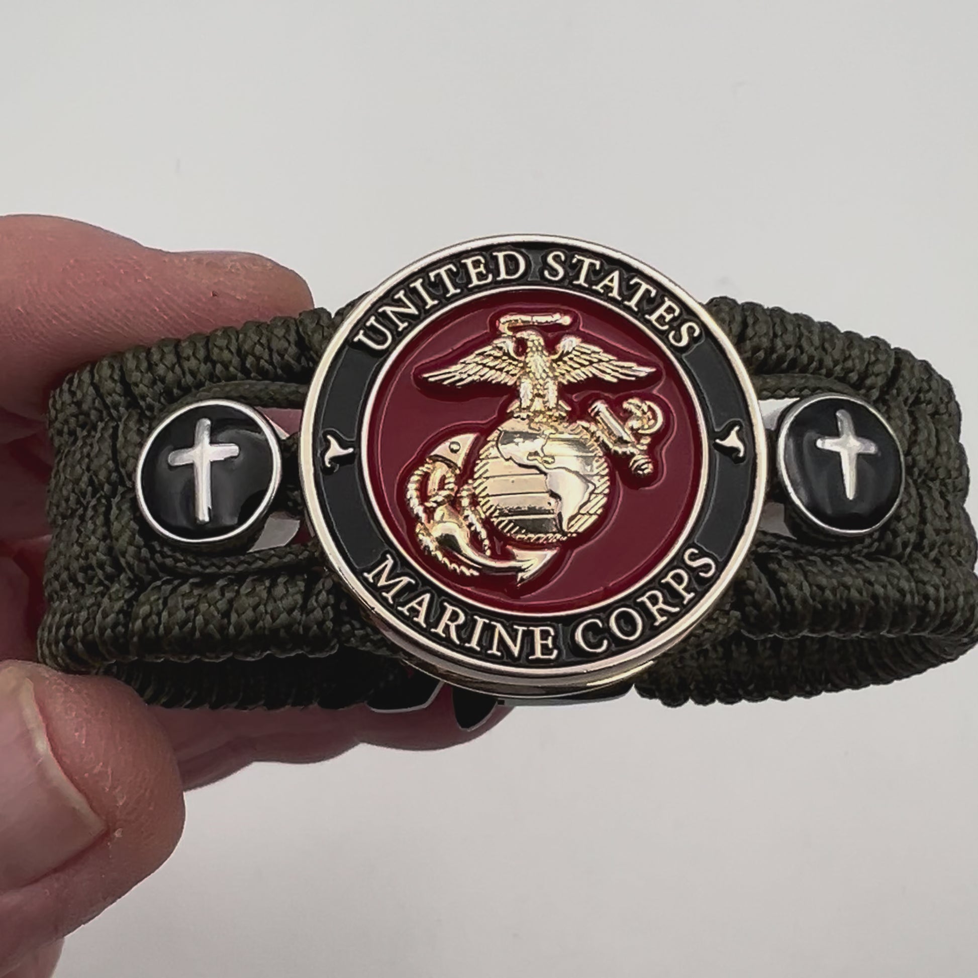 Thin, medium width, flexible and comfortable braided United States Marine Corps bracelet featuring a 24K gold plated USMC officer Eagle Globe and Anchor medallion, two Christian crosses, a black Cobra style tactical buckle and woven with Olive Drab Type-1 paracord.