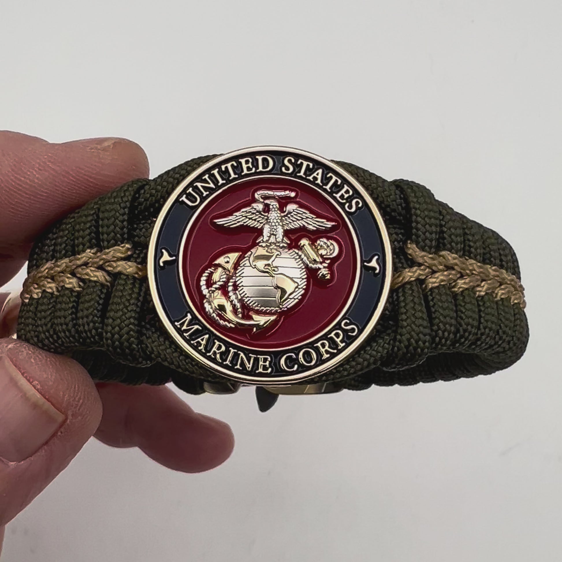 Thick, semi-rigid and comfortable braided United States Marine Corps bracelet featuring a 24K gold and silver plated USMC officer Eagle Globe and Anchor medallion, a gold Cobra style tactical buckle and woven with olive drab 550 and gold micro paracord.