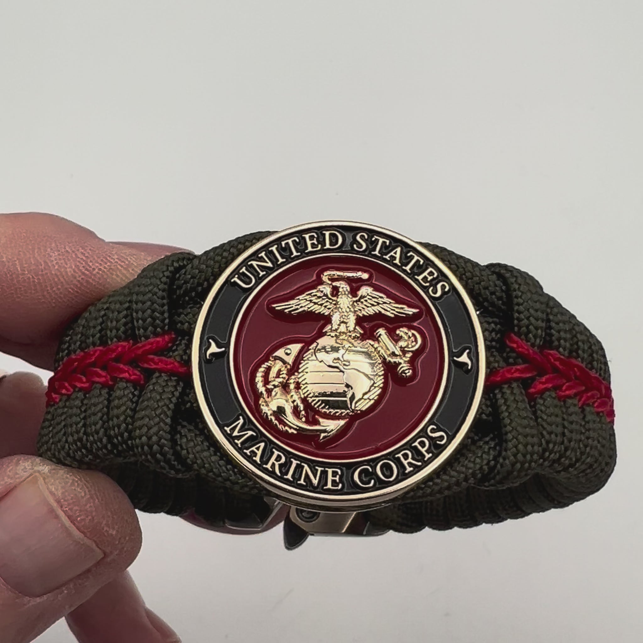 Thick, semi-rigid and comfortable braided United States Marine Corps bracelet featuring a 24K gold plated USMC officer Eagle Globe and Anchor medallion, a gold Cobra style tactical buckle and woven with olive drab 550 paracord and Imperial Red micro cord.