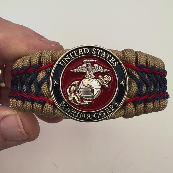 Thick and comfortable braided United States Marine Corps bracelet featuring a 24K gold and silver plated USMC officer Eagle Globe and Anchor medallion, a gold Cobra style tactical buckle and woven with gold 550 paracord and Imperial Red and Navy Blue micro cord.
