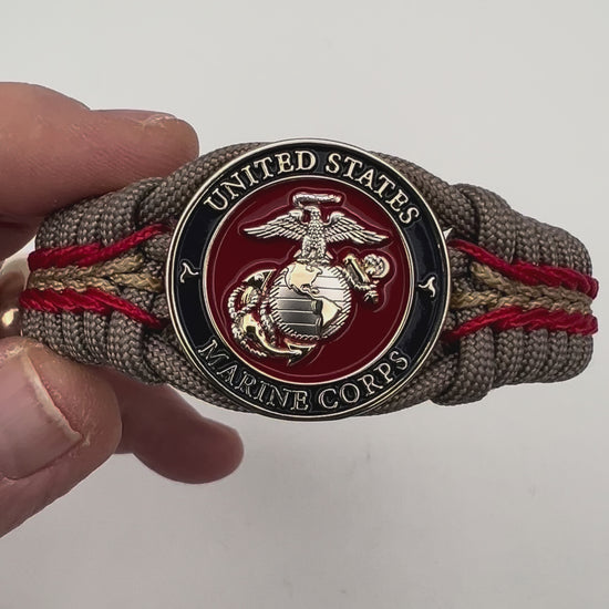 Thick and comfortable braided United States Marine Corps bracelet featuring a 24K gold and silver plated USMC officer Eagle Globe and Anchor medallion, a Cobra style tactical buckle and woven with tan 550, Imperial red and gold micro paracord.