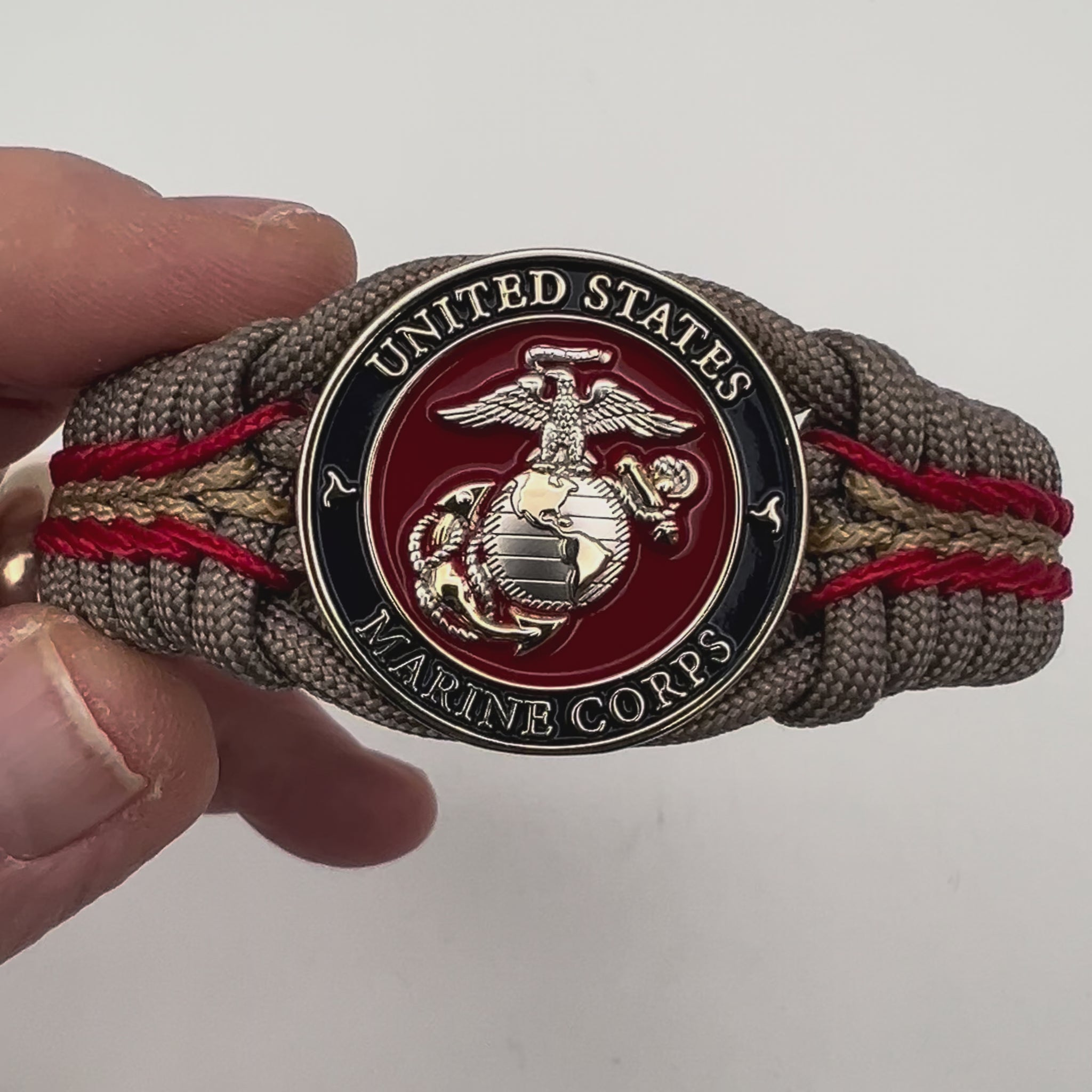 Thick and comfortable braided United States Marine Corps bracelet featuring a 24K gold and silver plated USMC officer Eagle Globe and Anchor medallion, a Cobra style tactical buckle and woven with tan 550, Imperial red and gold micro paracord.