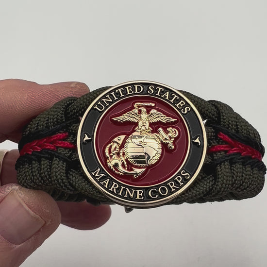 Thick, rigid and comfortable braided United States Marine Corps bracelet featuring a 24K gold plated USMC officer Eagle Globe and Anchor medallion, a gold Cobra style tactical buckle and woven with olive drab 550 paracord and black and Imperial red micro cord.
