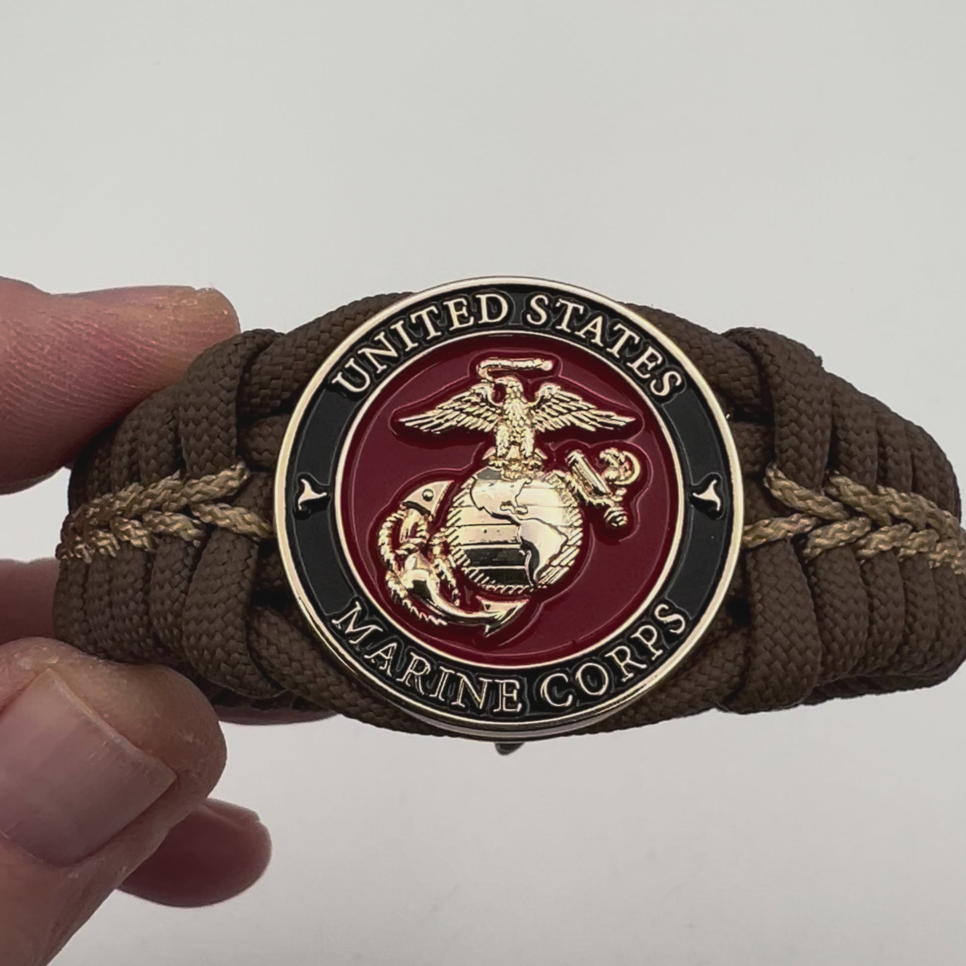 Thick, rigid and comfortable braided United States Marine Corps bracelet featuring a 24K gold plated USMC Eagle Globe and Anchor medallion, a gold Cobra style tactical buckle and woven with Coyote Brown 550 paracord and gold micro cord.