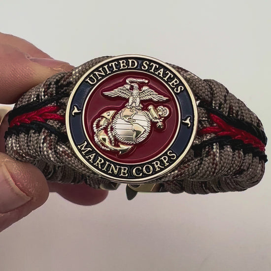 Thick and comfortable braided United States Marine Corps bracelet featuring a 24K gold and silver plated USMC officer Eagle Globe and Anchor medallion, a Cobra style tactical buckle and woven with Desert Camo 550 paracord and Imperial red and black micro cord.