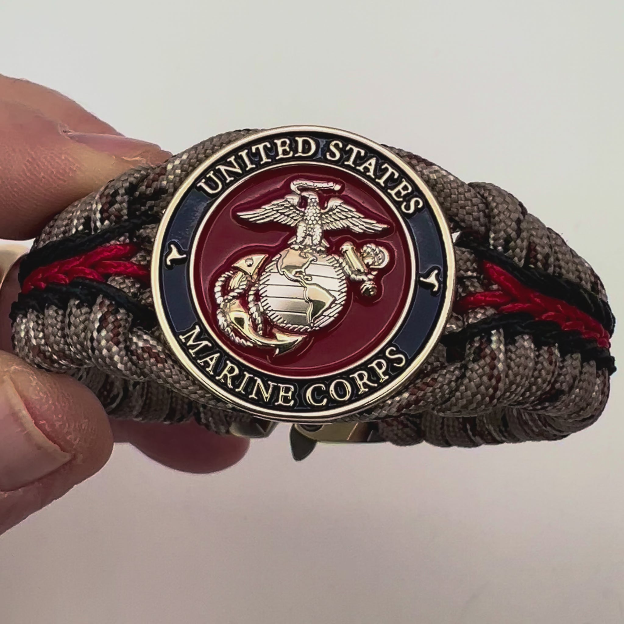 Thick and comfortable braided United States Marine Corps bracelet featuring a 24K gold and silver plated USMC officer Eagle Globe and Anchor medallion, a Cobra style tactical buckle and woven with Desert Camo 550 paracord and Imperial red and black micro cord.