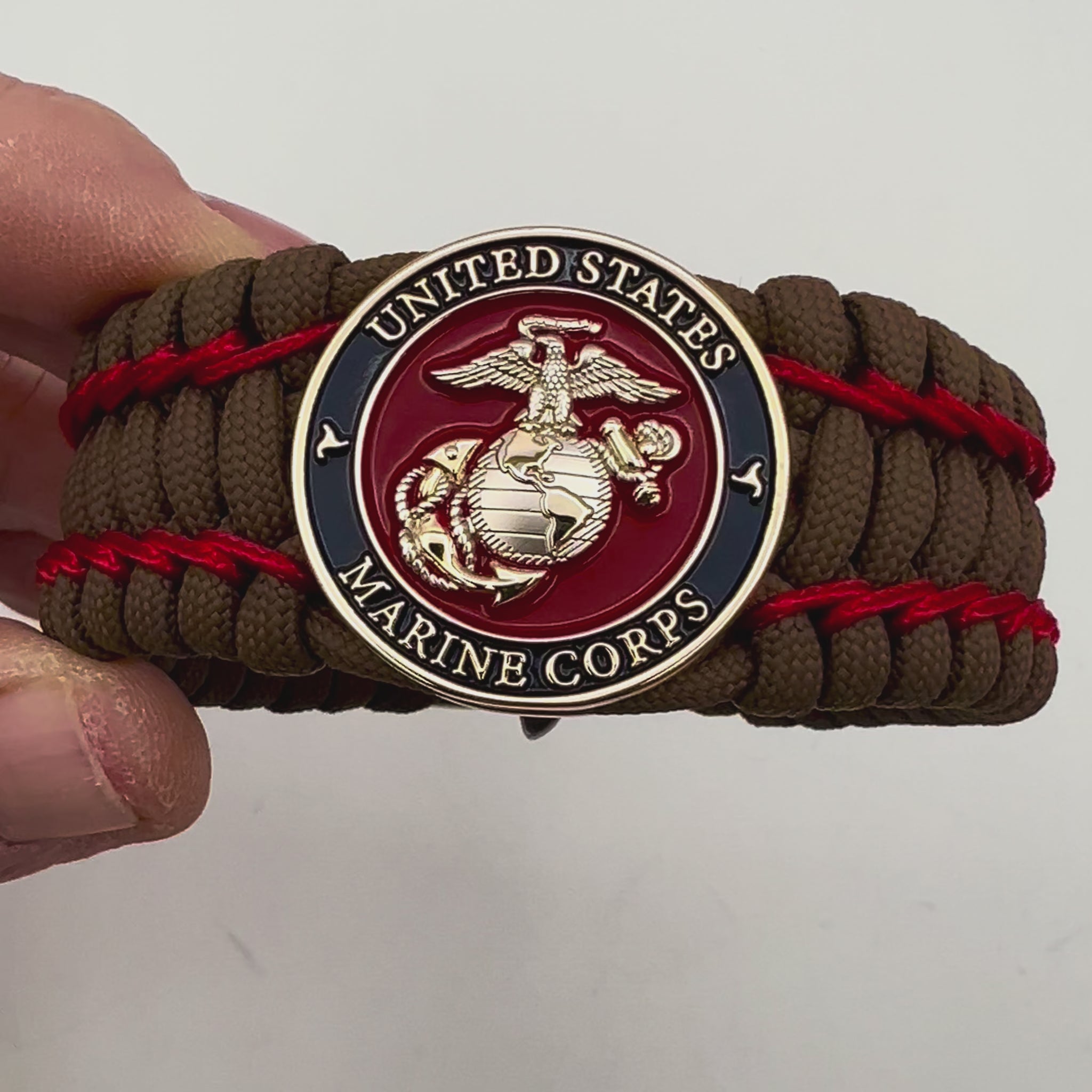 Thick and comfortable braided United States Marine Corps bracelet featuring a 24K gold and silver plated USMC officer Eagle Globe and Anchor medallion, a Cobra style tactical buckle and woven with Coyote Brown 550 paracord and Imperial Red micro cord.