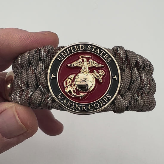 Thick, wide, semi-rigid and comfortable braided United States Marine Corps bracelet featuring a 24K gold plated USMC Eagle Globe and Anchor medallion, a gold Cobra style tactical buckle and woven with Desert Camo 550 paracord.