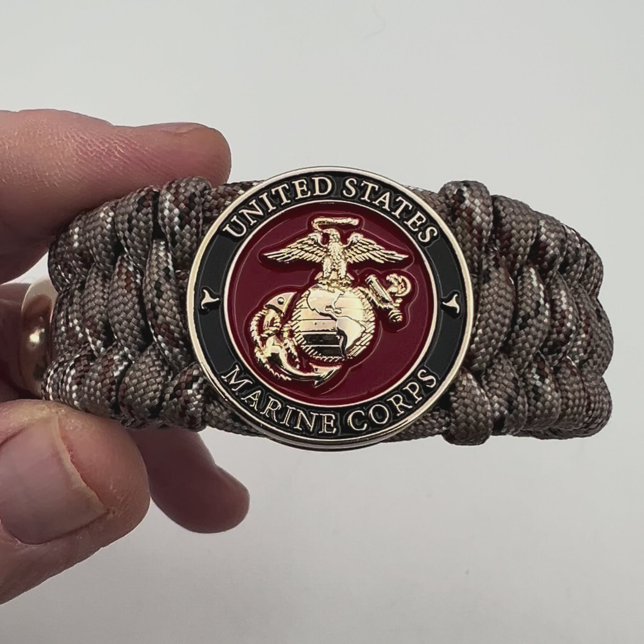 Thick, wide, semi-rigid and comfortable braided United States Marine Corps bracelet featuring a 24K gold plated USMC Eagle Globe and Anchor medallion, a gold Cobra style tactical buckle and woven with Desert Camo 550 paracord.