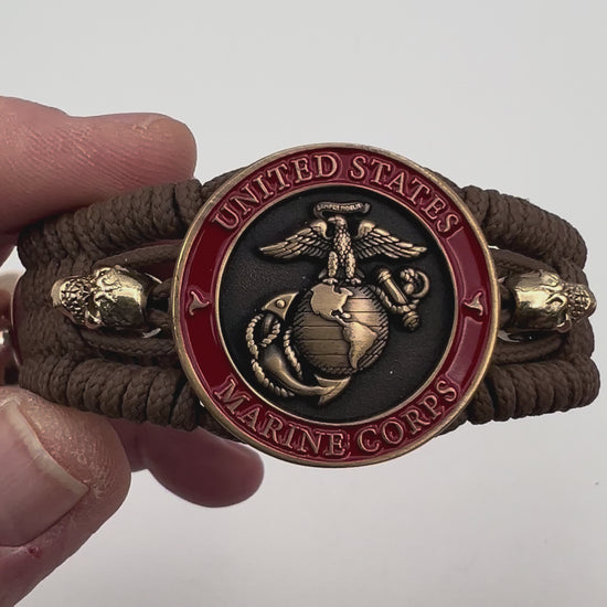 Thin, medium width, flexible and comfortable braided United States Marine Corps bracelet featuring a 24K antique gold plated USMC officer Eagle Globe and Anchor medallion, two gold plated skulls, a gold Cobra style tactical buckle and woven with Coyote Brown Type-1 paracord.