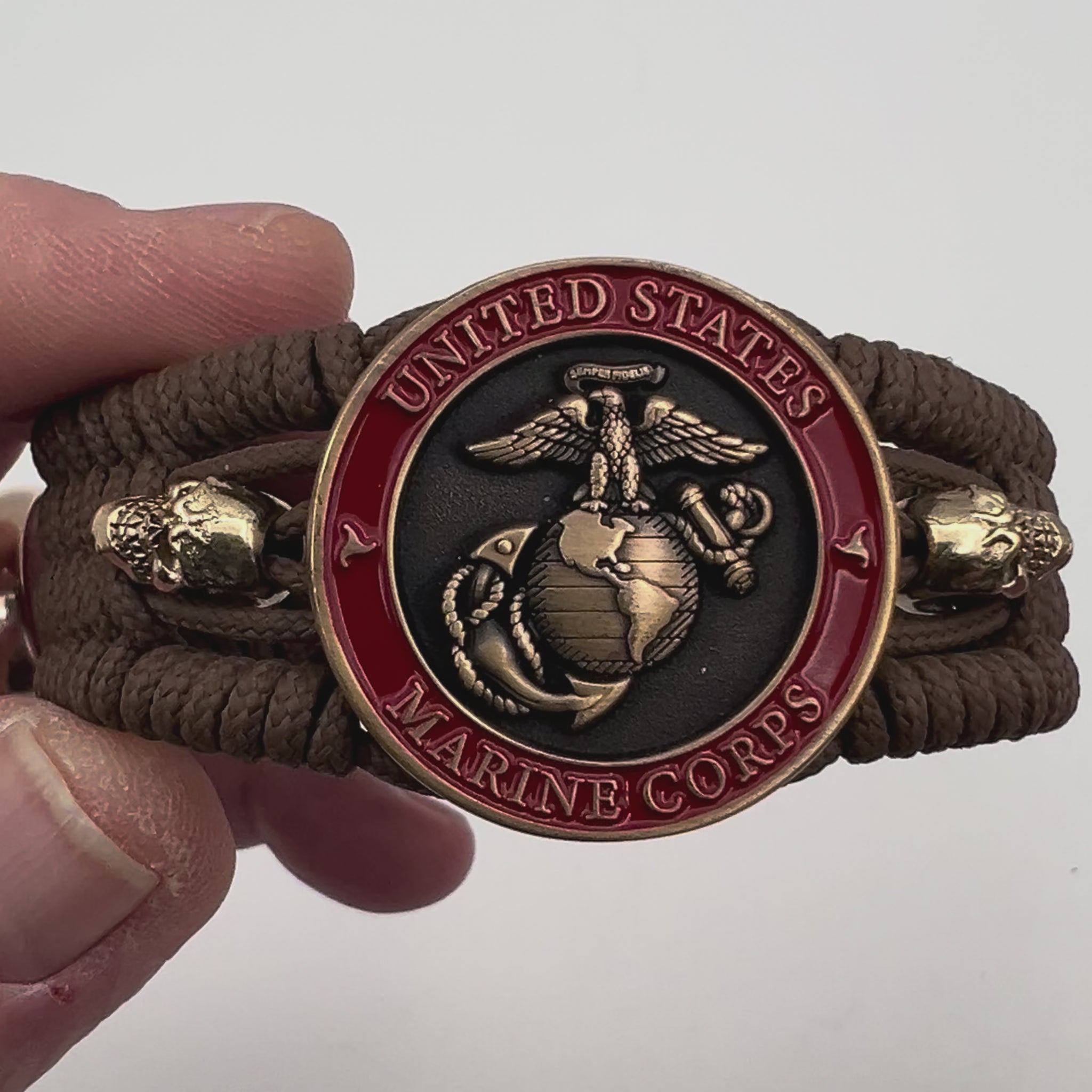 Thin, medium width, flexible and comfortable braided United States Marine Corps bracelet featuring a 24K antique gold plated USMC officer Eagle Globe and Anchor medallion, two gold plated skulls, a gold Cobra style tactical buckle and woven with Coyote Brown Type-1 paracord.