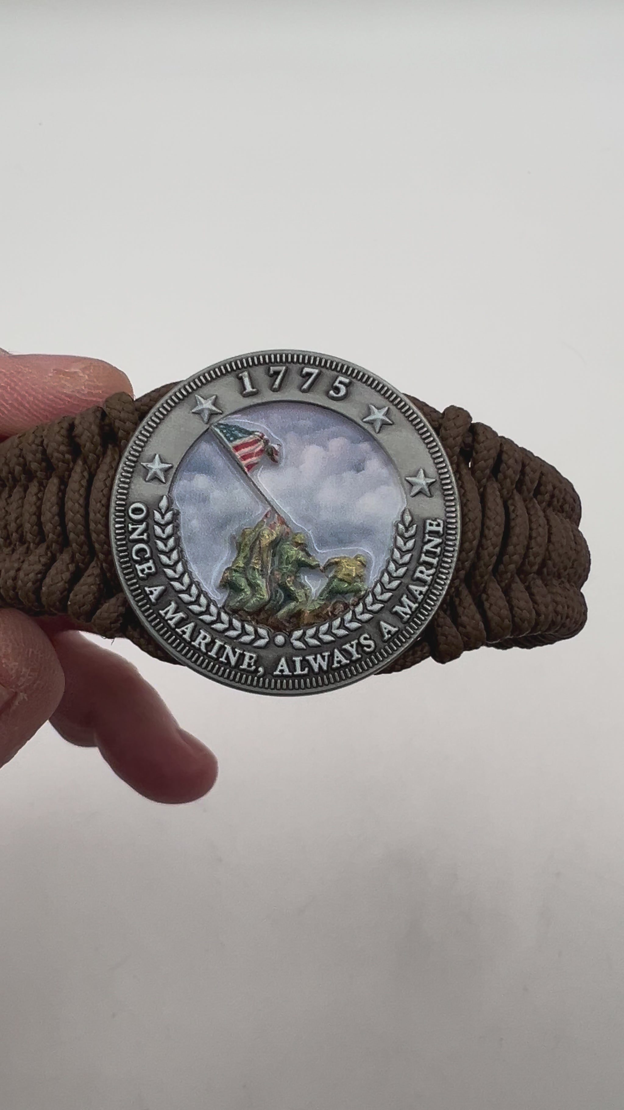 Thin, narrow, flexible and comfortable braided United States Marine Corps Iwo Jima bracelet featuring an antique silver plated UV painted Iwo Jima flag raising medallion, a silver Cobra style tactical buckle and woven with Coyote Brown type-1 paracord.
