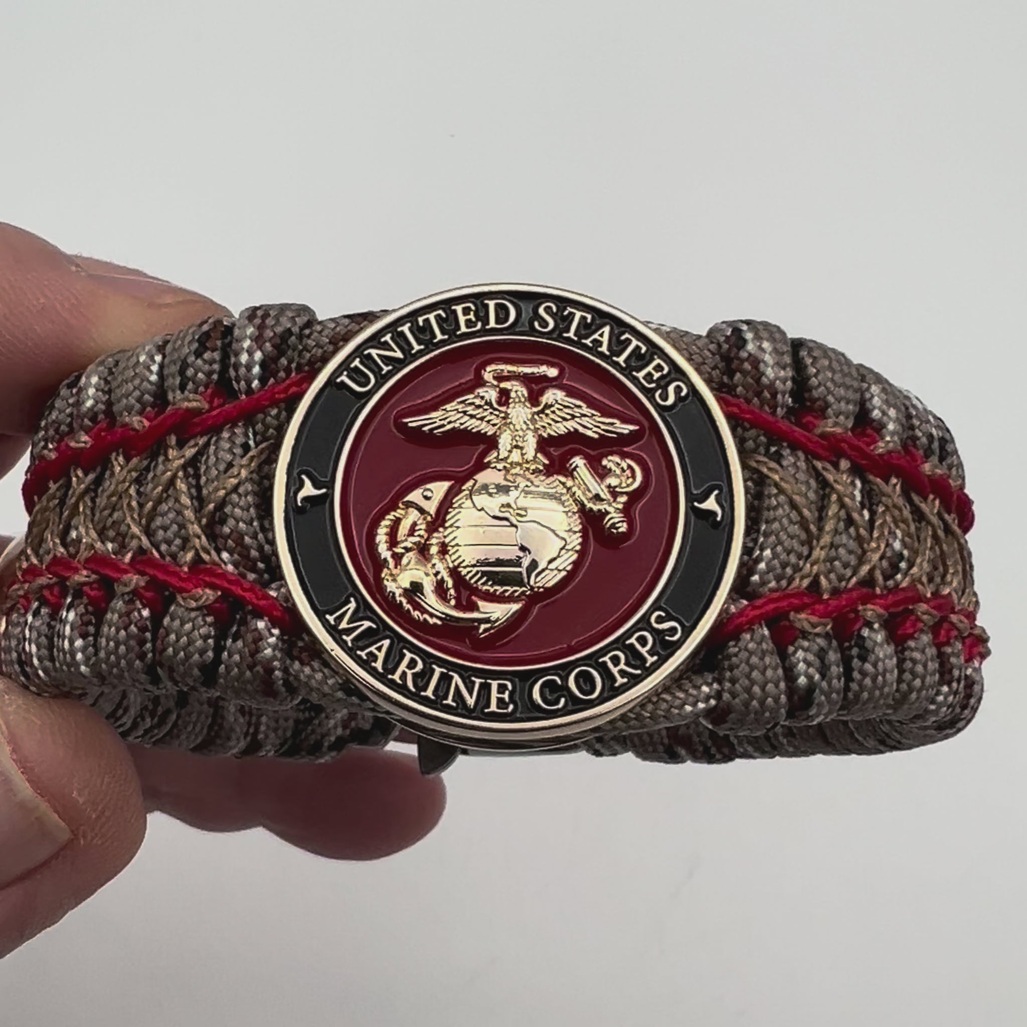 Thick, wide, rigid and comfortable braided United States Marine Corps bracelet featuring a 24K gold plated USMC Eagle Globe and Anchor medallion, a gold Cobra style tactical buckle and woven with Desert Camo 550 paracord and Imperial Red micro and gold nano cord.
