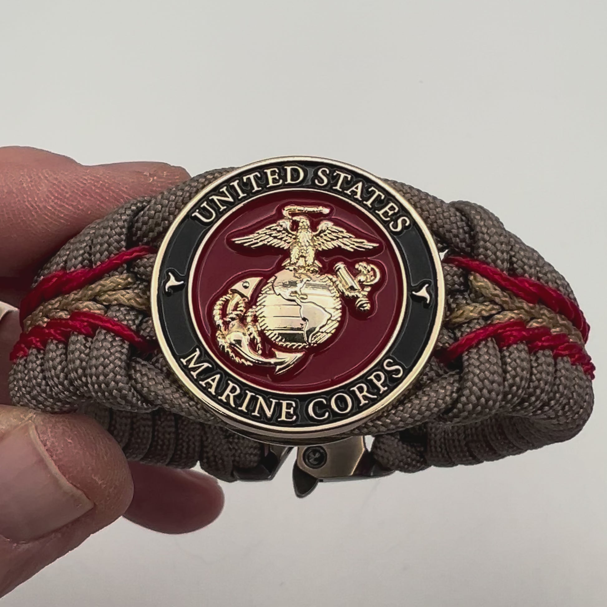 Thick, rigid and comfortable braided United States Marine Corps bracelet featuring a 24K gold plated USMC Eagle Globe and Anchor medallion, a gold Cobra style tactical buckle and woven with tan 550 paracord and Imperial Red and gold micro cord.