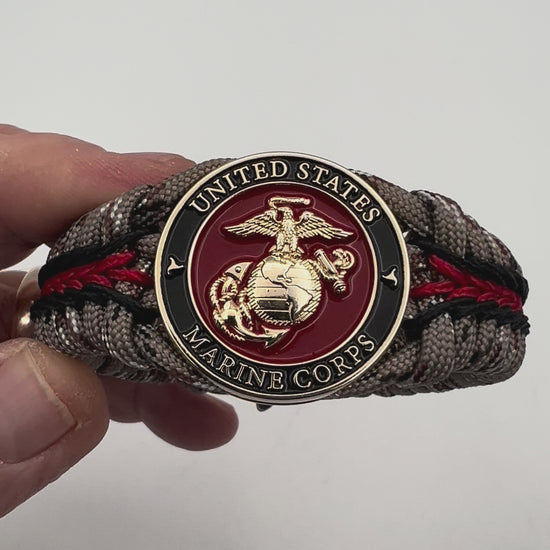 Thick, rigid and comfortable braided United States Marine Corps bracelet featuring a 24K gold plated USMC Eagle Globe and Anchor medallion, a gold Cobra style tactical buckle and woven with Desert Camo 550 paracord and black and Imperial Red micro cord.